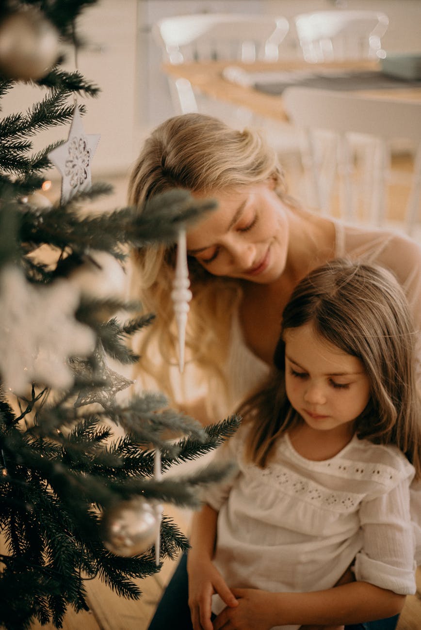 woman and girl standing beside christmas tree