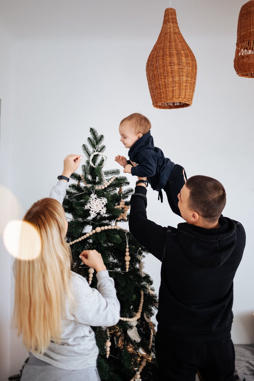 man holding baby up to christmas tree