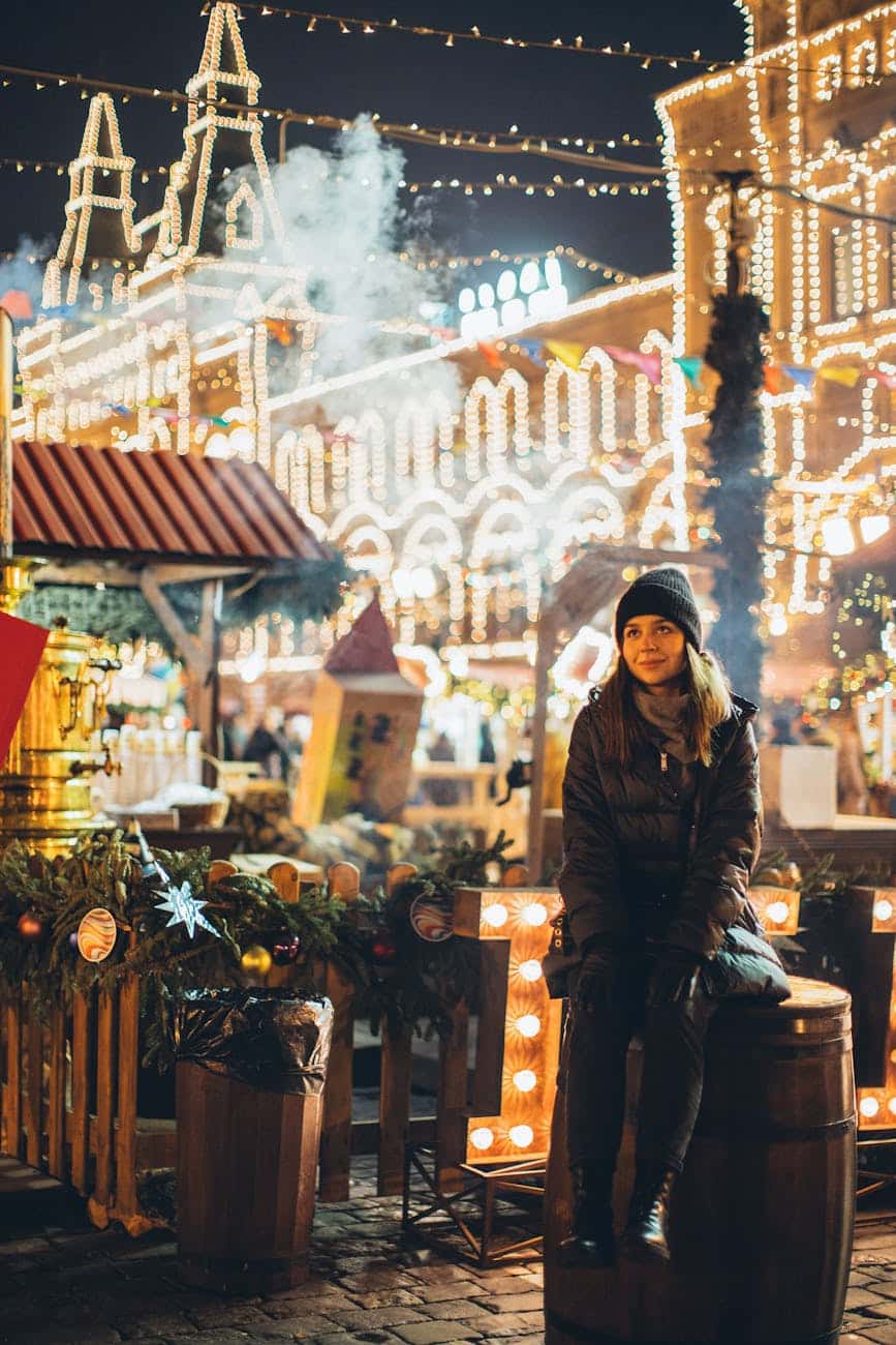 dreamy woman in warm wear on square at new year night