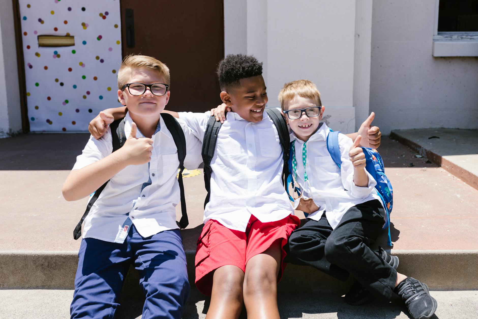 boys sitting on concrete stairs with thumbs up