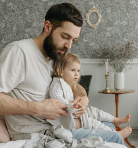man in white shirt with a child sitting on the bed