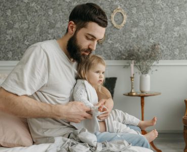 man in white shirt with a child sitting on the bed