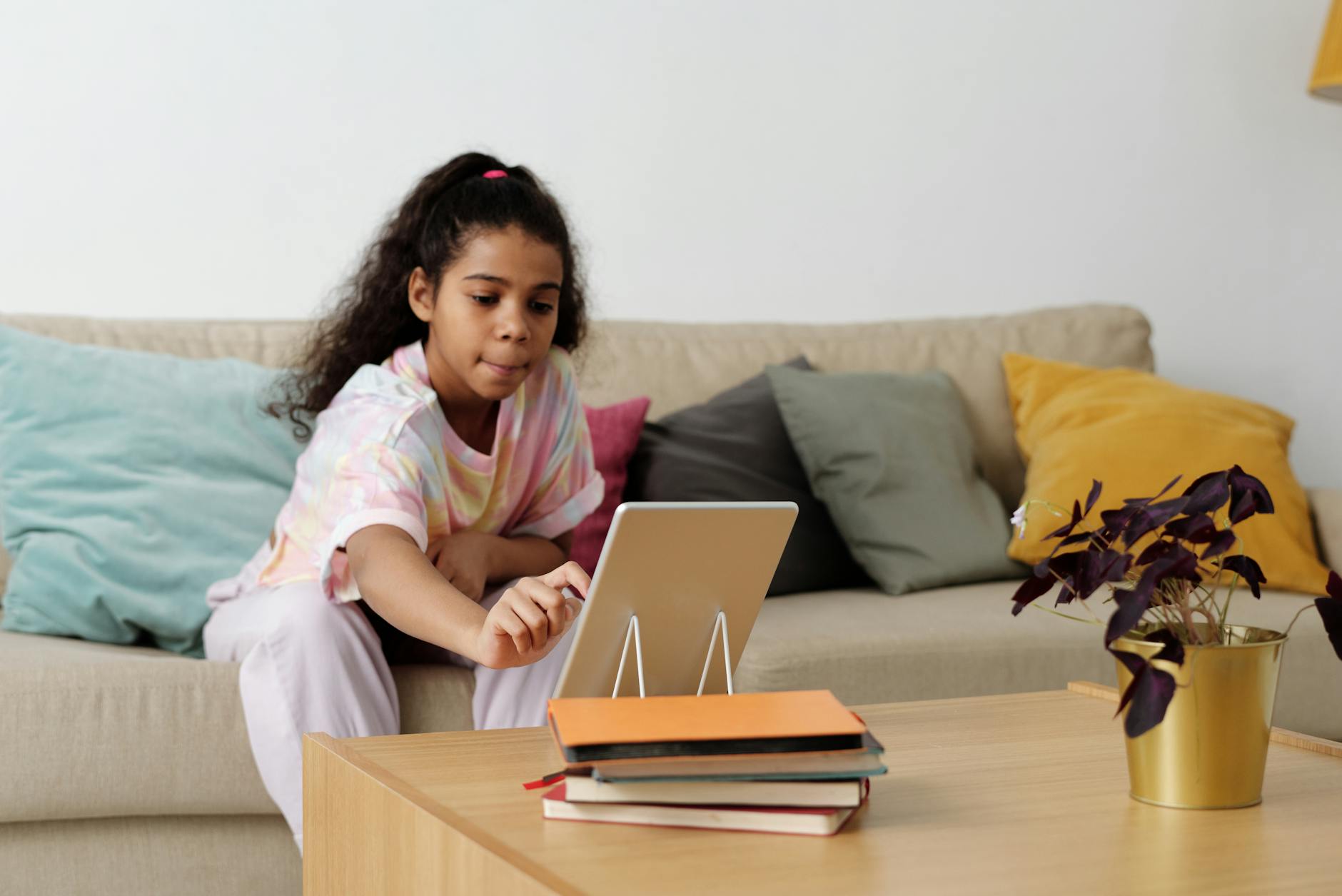 girl sitting on sofa while using tablet computer