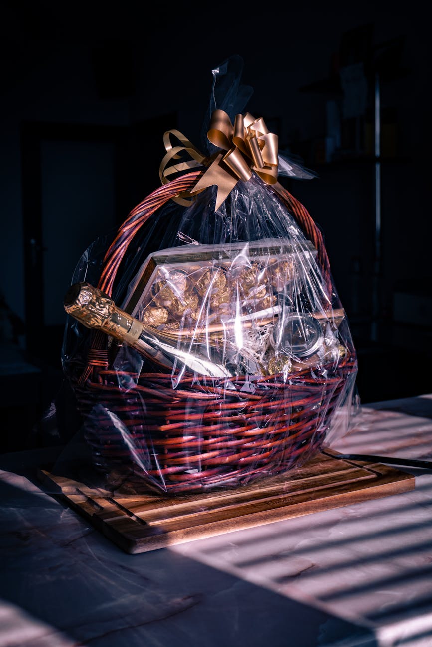 present basket with a ribbon champagne and chocolate sweets on a dark background