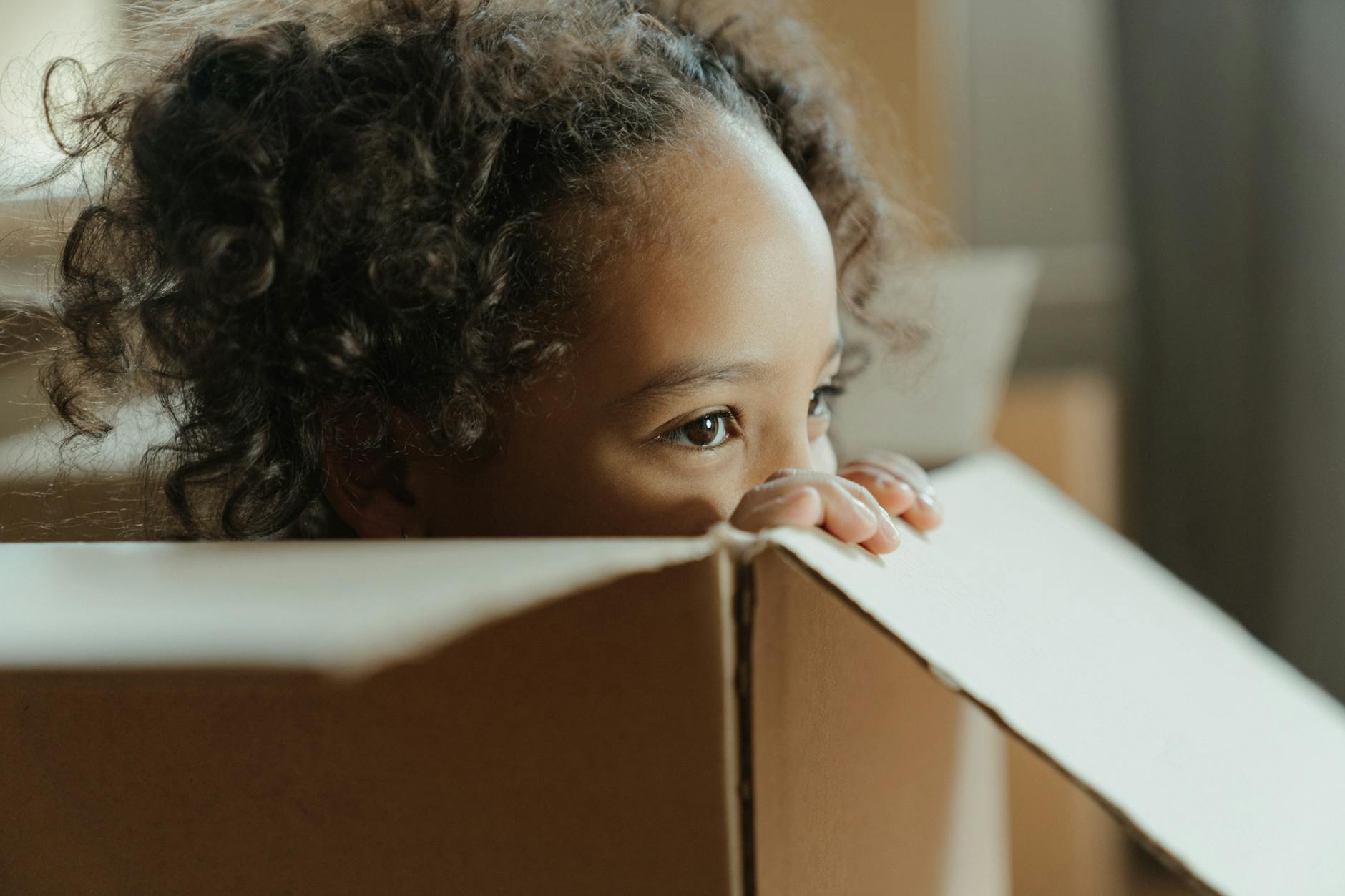 girl in white shirt lying on brown cardboard box