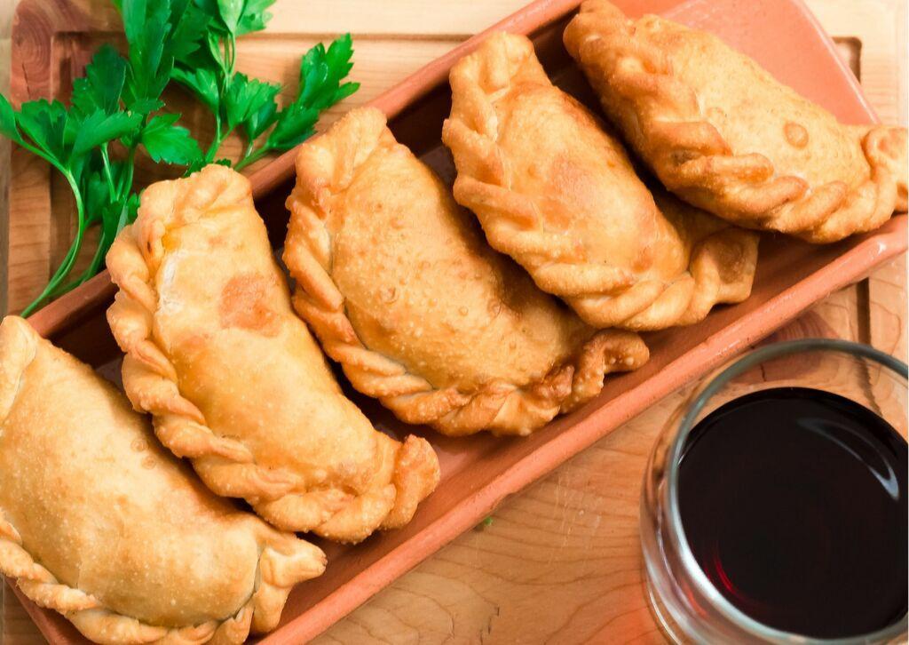 Traditional cornish pasties displayed on tray with red wine.