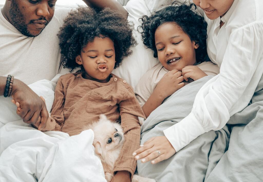 parents with two kids together in bed