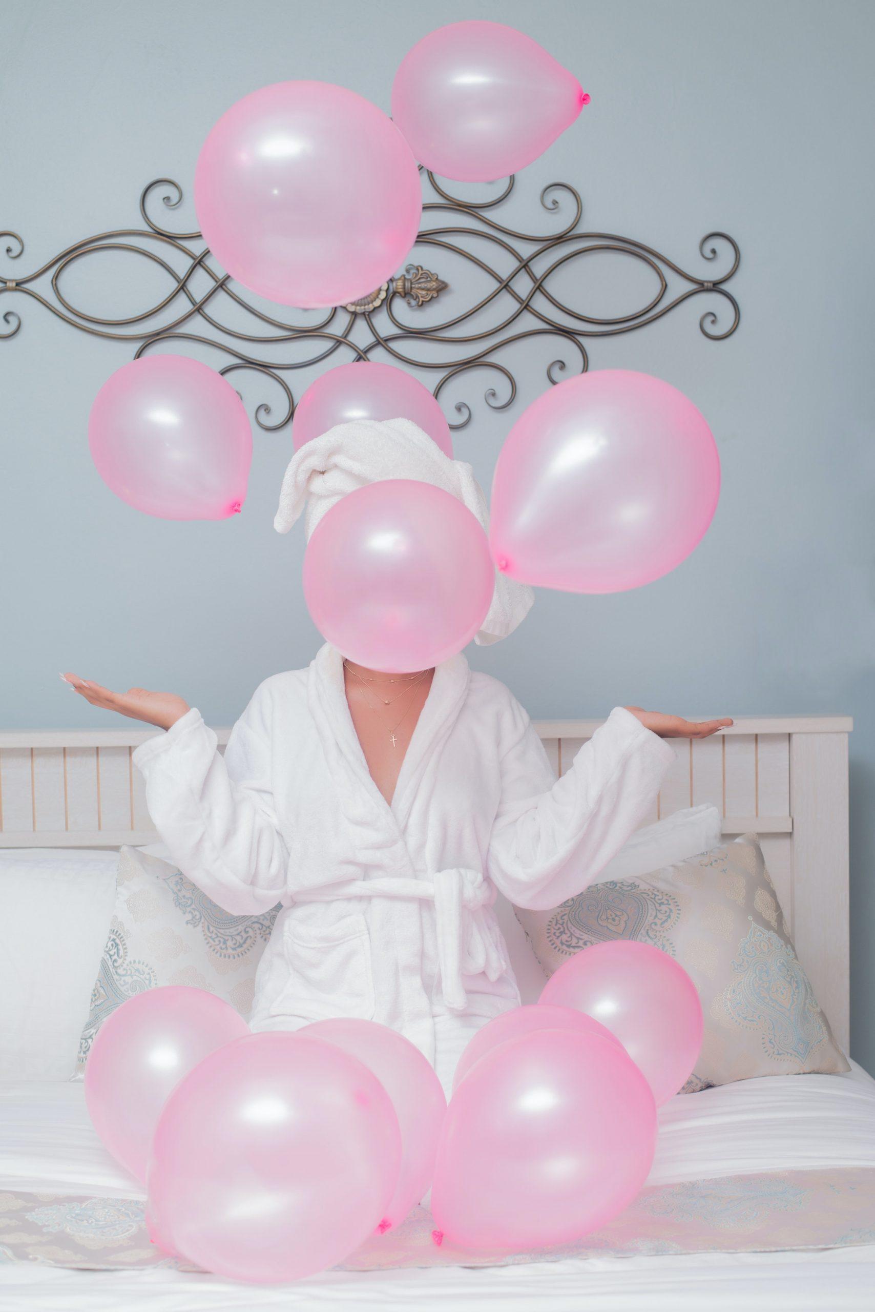 Woman in White Robe Playing With Pink Balloons
