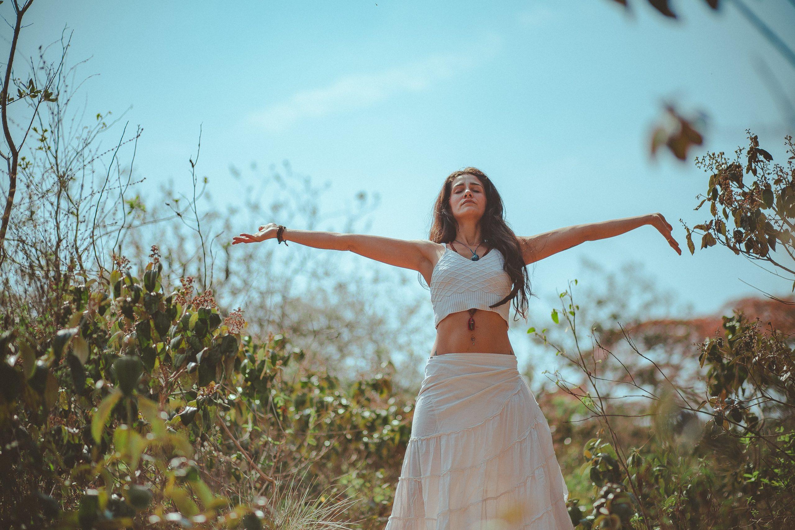 Girl in a white top and cream skirt, holding her arms out