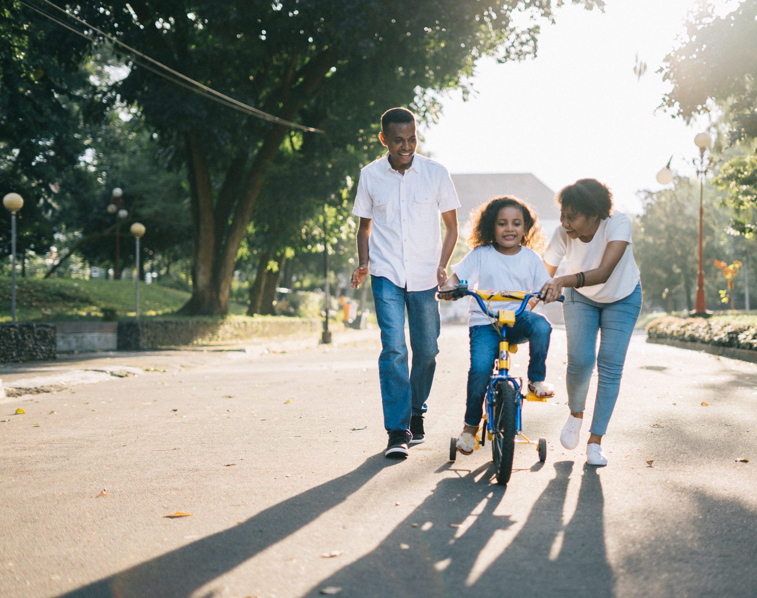 Parents helping their child to learn how to ride a bike