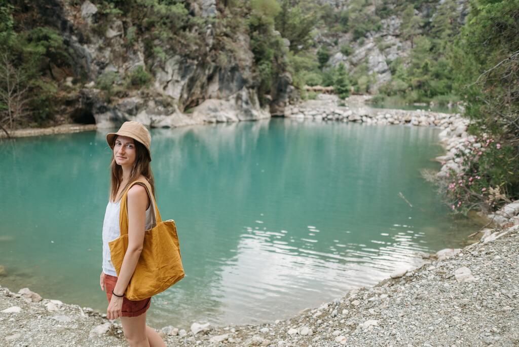 Women with white top standing in front of lake.
