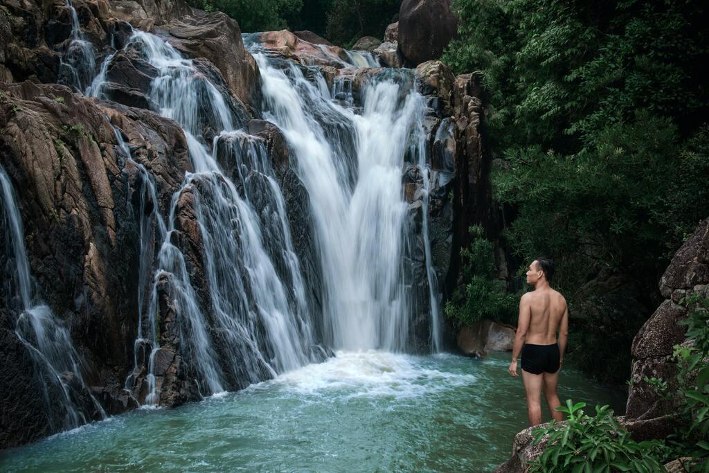 Young man standing in front of a waterfall