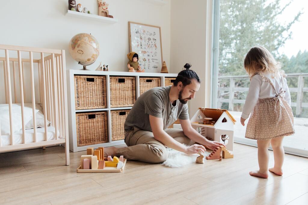 A dad and his daughter are playing with toys.