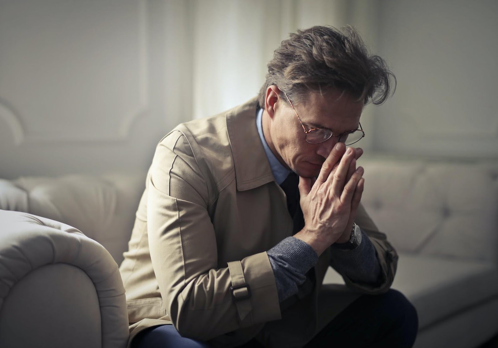 Sad mature businessman thinking about problems in living room