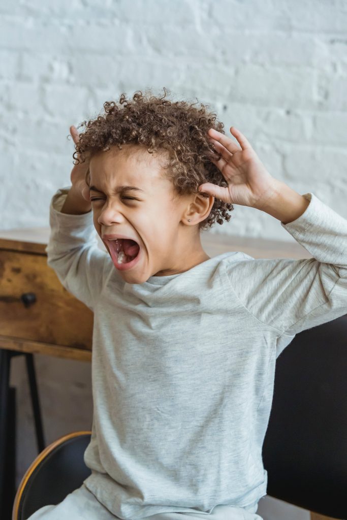 Little boy in grey top screaming from frustration