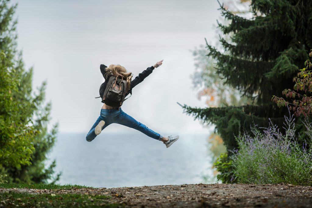 Woman jumping in air with green rucksack