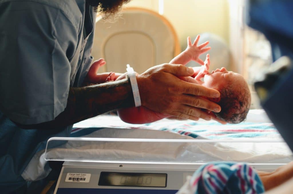 Newborn baby being weighed by midwife