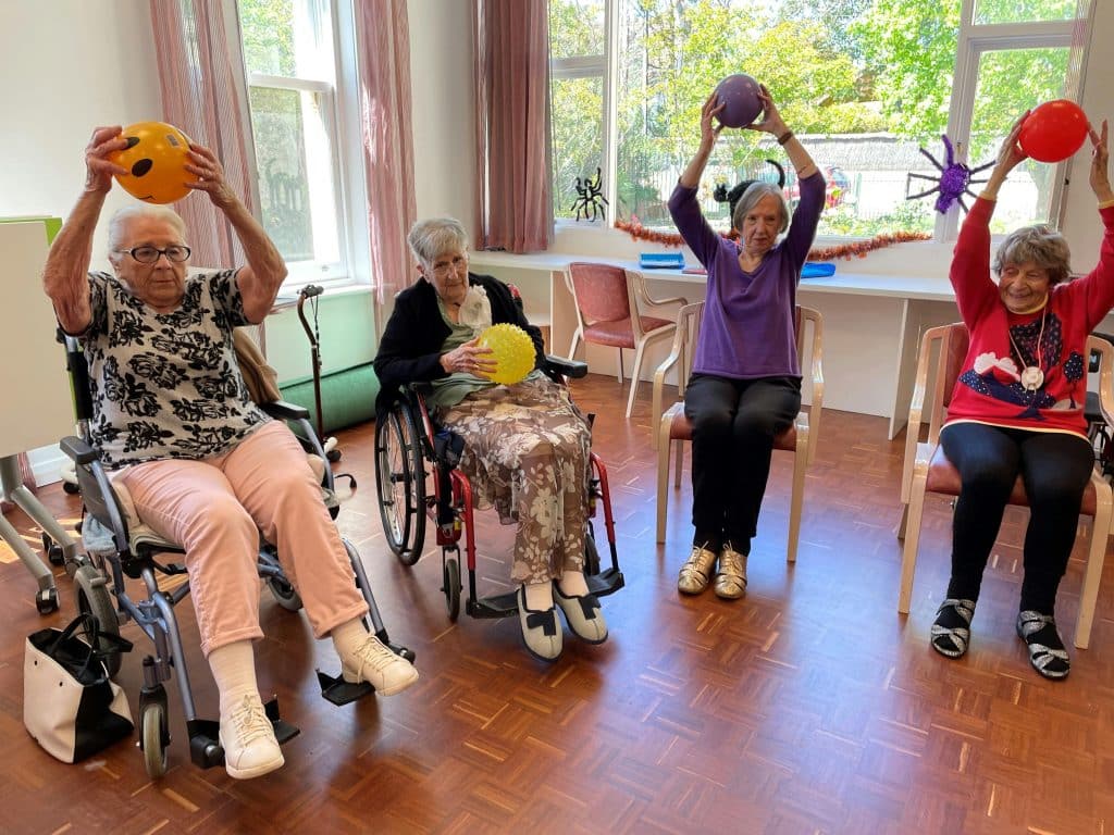 Four women holding balls above their heads in respite center