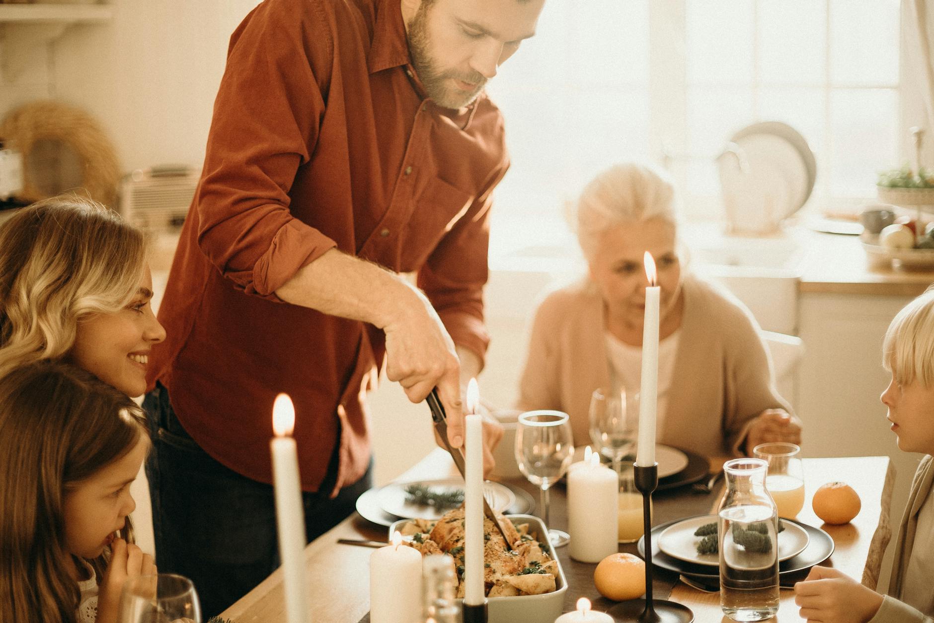 selective focus photography of man preparing food beside smiling women and kids