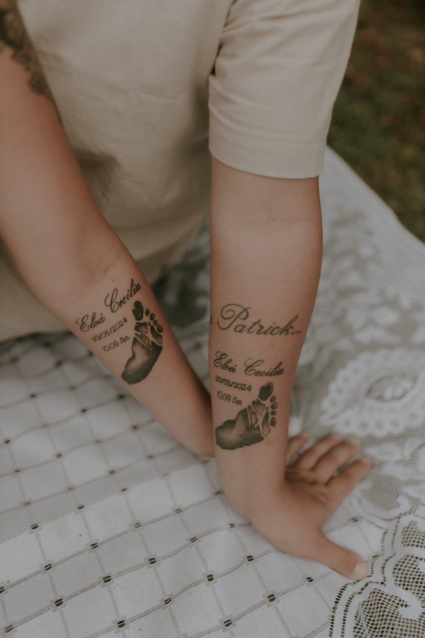 tattooed arms with baby footprints and names