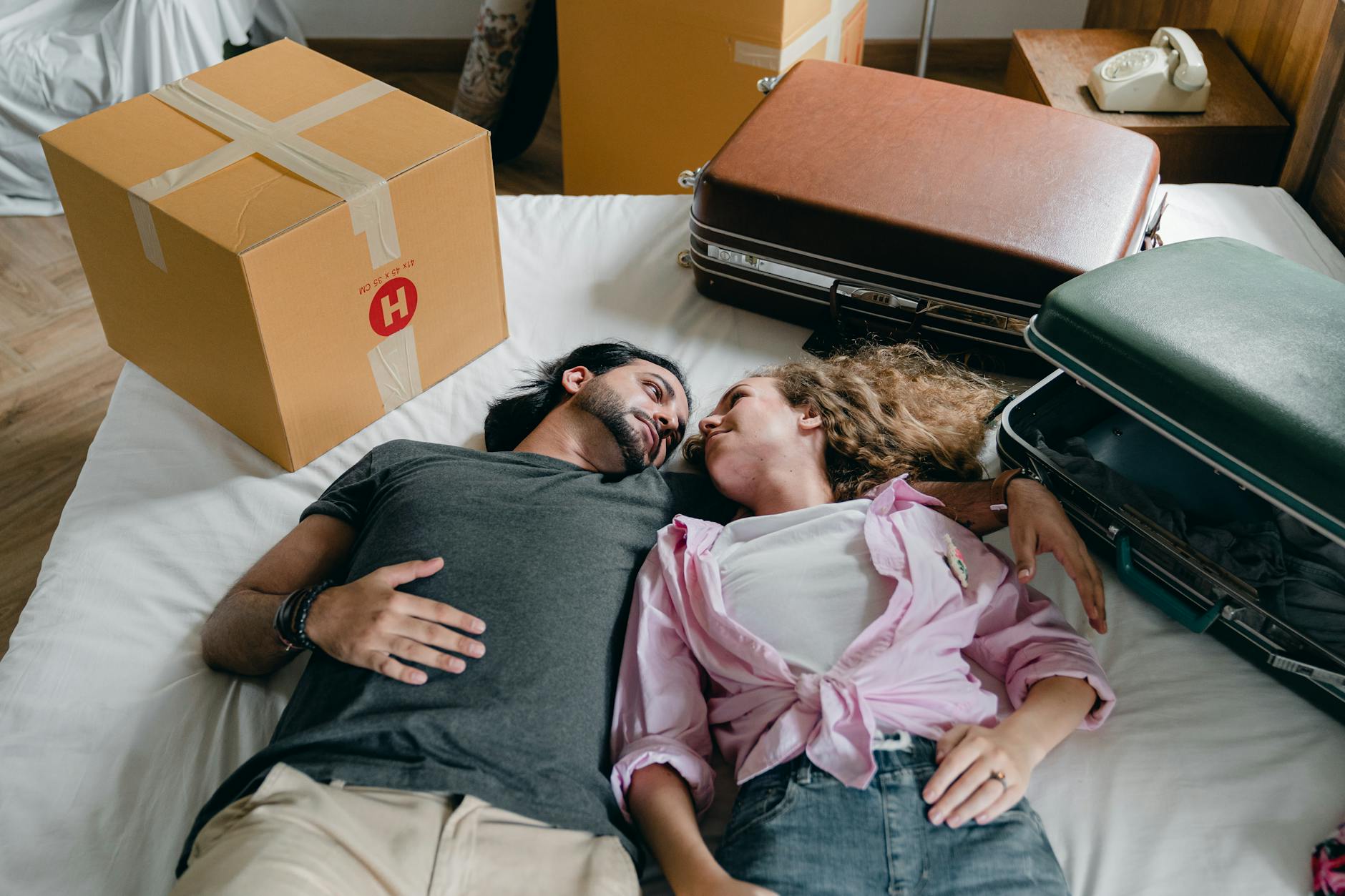 embracing diverse couple lying on bed during relocation in new house