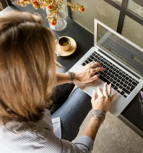 person sitting while typing on gray laptop