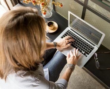 person sitting while typing on gray laptop