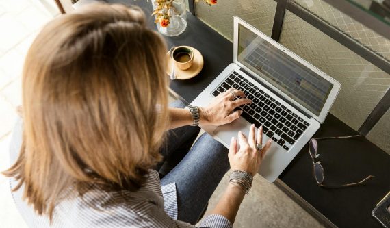 person sitting while typing on gray laptop
